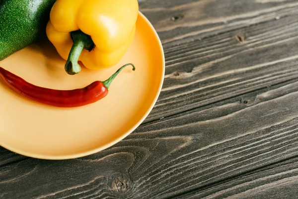 Pimienta de chile con aguacate y pimiento en plato sobre mesa de madera - foto de stock