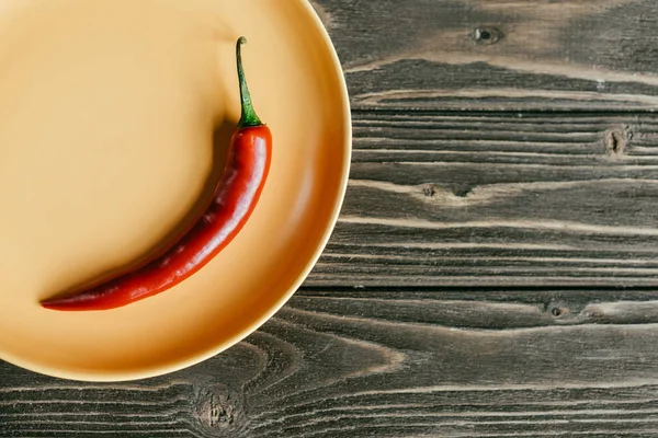 Red hot pepper served on plate on wooden table — Stock Photo