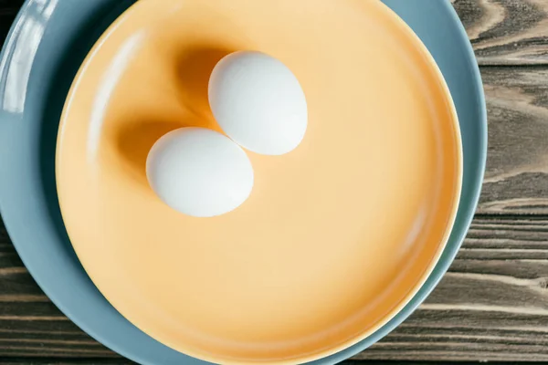 Uova di pollo bianco sul piatto sul tavolo di legno — Foto stock