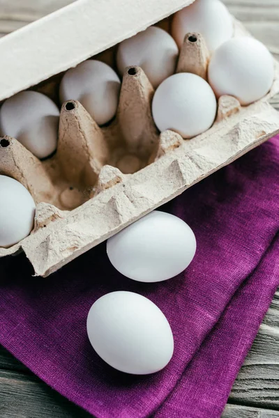 Huevos de pollo en caja en servilleta púrpura - foto de stock