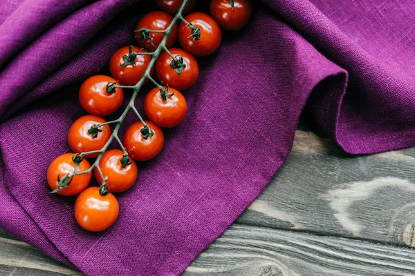 Branche de tomates cerises sur serviette violette — Photo de stock
