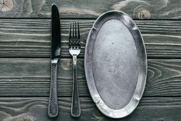 Knife and fork with silver tray on wooden table — Stock Photo