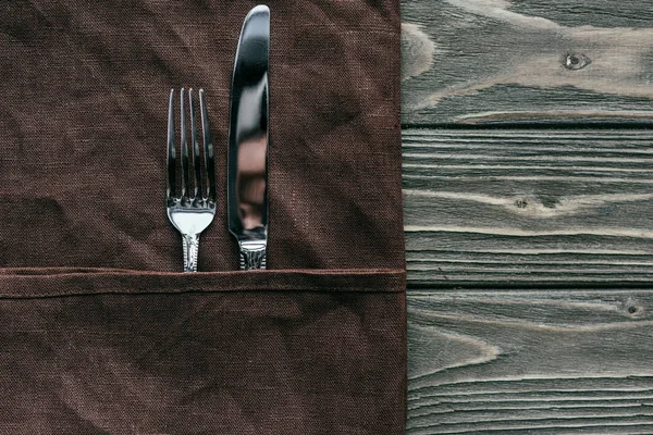 Silverware set with brown napkin on wooden table — Stock Photo