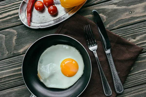 Raw vegetables and frying pan with egg on textile napkin — Stock Photo