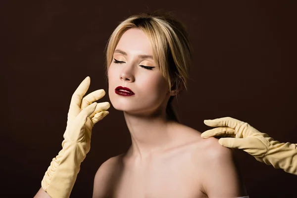 Mains humaines en gants jaunes touchant séduisante fille blonde nue sur brun — Photo de stock