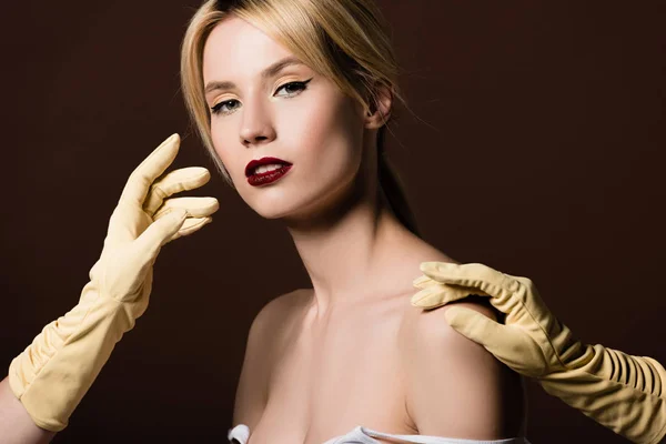 Human hands in yellow gloves and sensual naked girl looking at camera on brown — Stock Photo