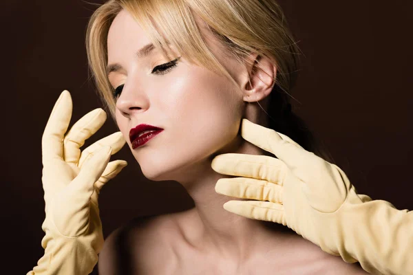 Sensual naked blonde girl and human hands in yellow gloves on brown — Stock Photo