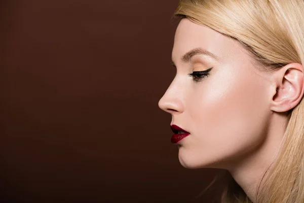 Profile portrait of beautiful young blonde woman looking away isolated on brown — Stock Photo