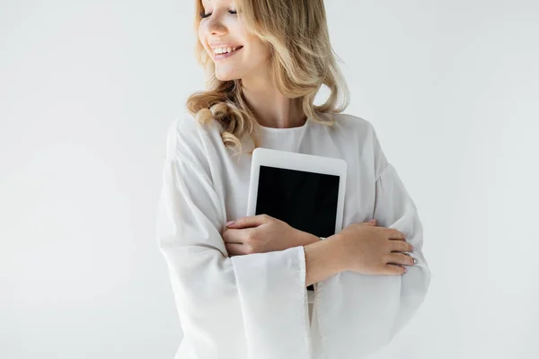 Portrait of young smiling woman in white clothing with tablet on grey backdrop — Stock Photo