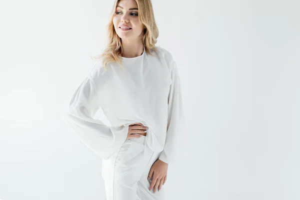 Portrait of smiling blond woman in white clothing posing on white backdrop — Stock Photo