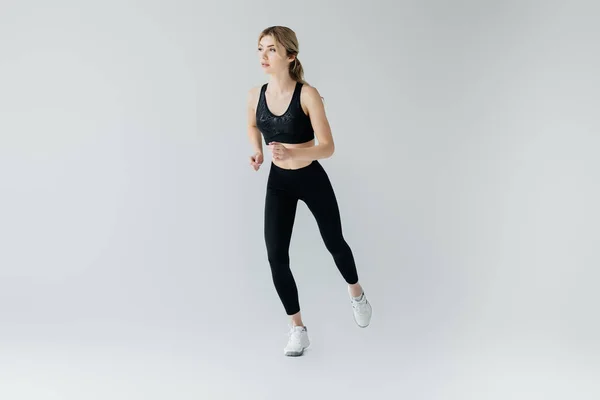 Young athletic sportswoman exercising isolated on grey — Stock Photo