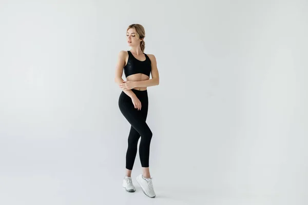 Young blond sportswoman in black sportswear posing isolated on grey — Stock Photo