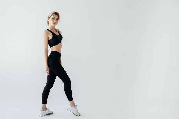 Side view of young blond sportswoman in black sportswear posing isolated on grey — Stock Photo