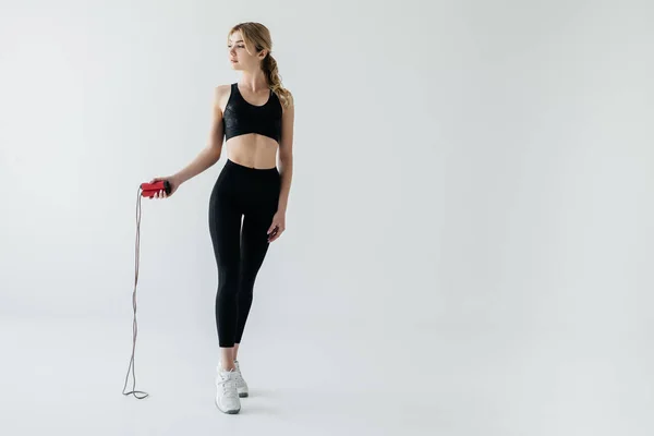 Jeune femme sportive avec corde à sauter isolée sur gris — Photo de stock