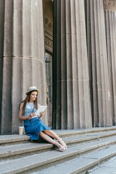 Ganzkörperansicht der schönen jungen Frau, die auf einer Treppe sitzt und ein digitales Tablet benutzt — Stockfoto
