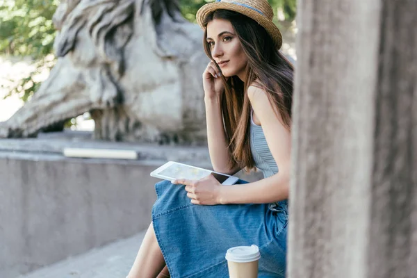 Chère jeune femme avec tablette numérique assis sur les escaliers et regardant loin — Photo de stock