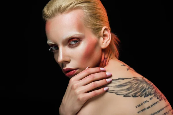 Attraente ragazza alla moda con ali tatuate, isolato su nero — Foto stock