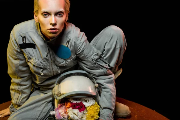 Cosmonauta em traje espacial com flores em capacete sentado no planeta — Fotografia de Stock