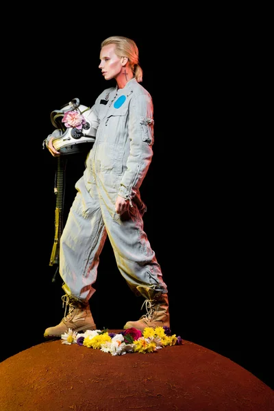 Hermosa mujer del espacio en traje espacial con flores y casco de pie en el planeta rojo - foto de stock