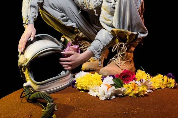 Cropped view of astronaut in spacesuit with flowers and helmet sitting on mars — Stock Photo