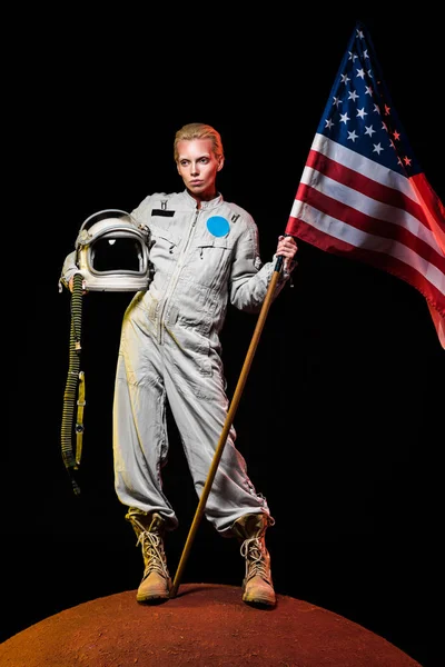 Beautiful astronaut in spacesuit holding helmet and american flag on red planet — Stock Photo