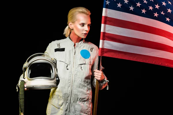 Cosmonaut in spacesuit holding helmet and american flag, isolated on black — Stock Photo