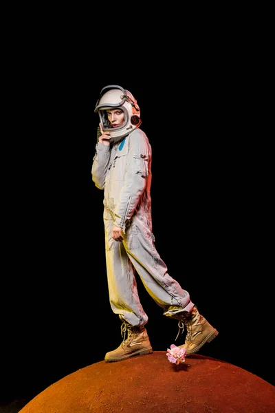 Cosmonauta en traje espacial y casco de pie sobre flor de peonía en el planeta - foto de stock