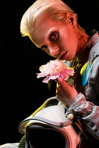 Attractive female astronaut in spacesuit with helmet and flower, on black — Stock Photo