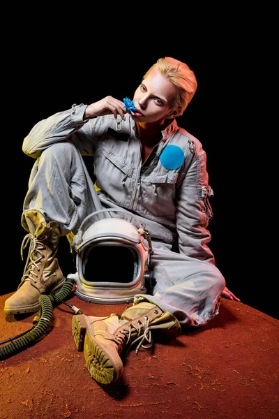 Belo astronauta em traje espacial com flor e capacete sentado no planeta — Fotografia de Stock