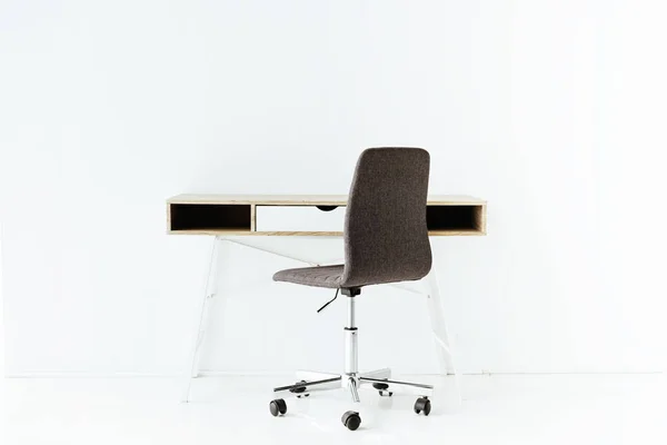 Elegante mesa de trabajo vacía y silla de ruedas delante de la pared blanca - foto de stock