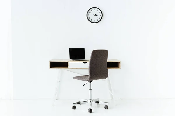 Lugar de trabajo con portátil frente a la pared blanca en la oficina - foto de stock