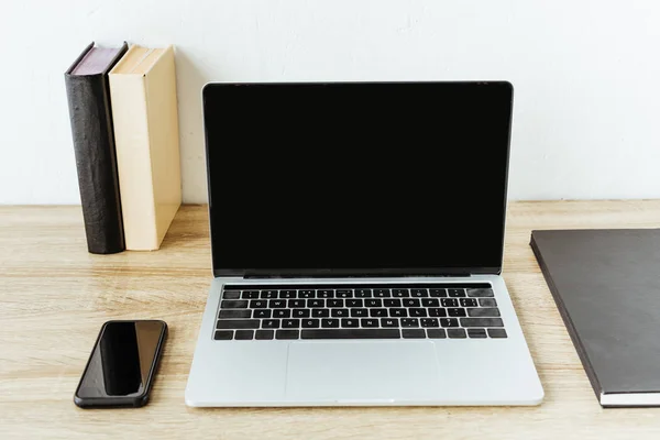 Ordinateur portable avec smartphone et livres sur la table de travail au bureau — Photo de stock