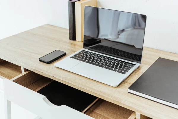 Laptop with smartphone and books on work desk at office — Stock Photo