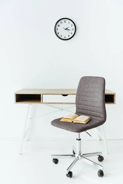 Mobiliário de escritório elegante com livro velho na frente da parede branca com relógio — Fotografia de Stock