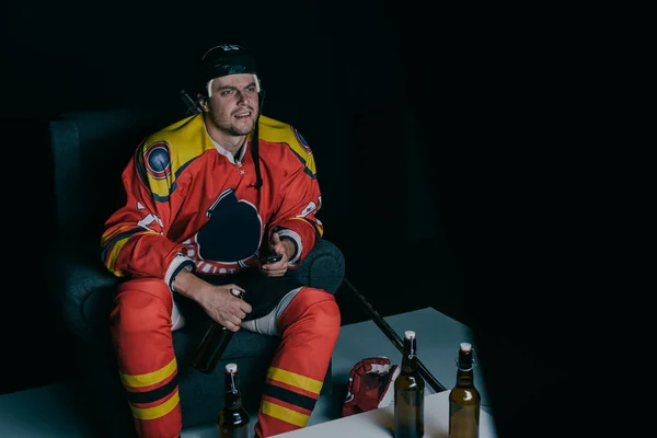 Giocatore di hockey emotivo bere birra e guardare la tv su nero — Foto stock
