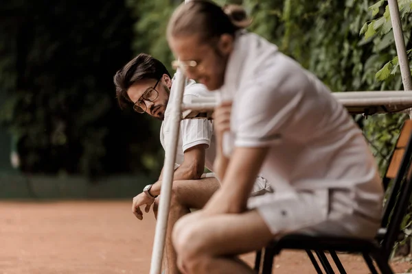 Vue latérale des joueurs de tennis de style rétro assis sur des chaises au court de tennis — Photo de stock