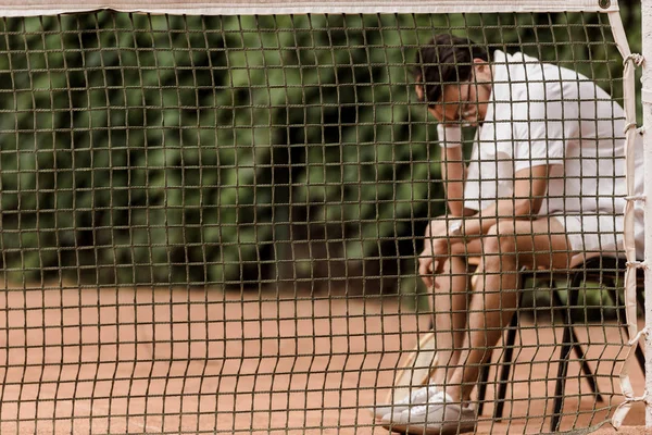 Теннисист сидит на стуле над сеткой на теннисном корте — стоковое фото