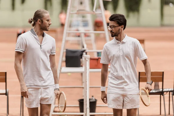 Retro styled tennis players walking and looking at each other before game at tennis court — Stock Photo