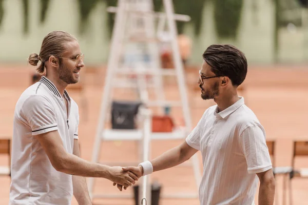 Side view of retro styled tennis players shaking hands before game at tennis court — Stock Photo