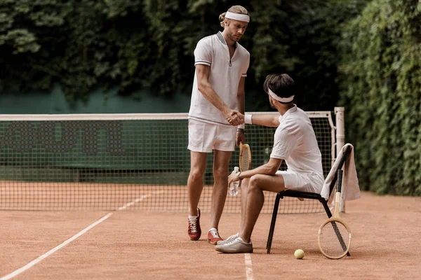 Jugadores de tenis estilo retro estrechando la mano en la cancha de tenis - foto de stock