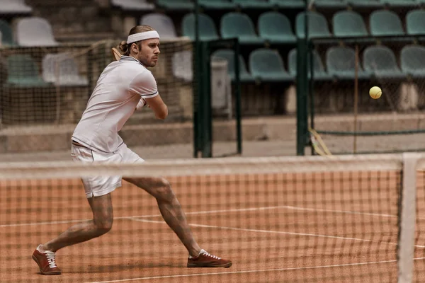 Enfocado guapo retro estilo hombre jugando tenis en la corte - foto de stock