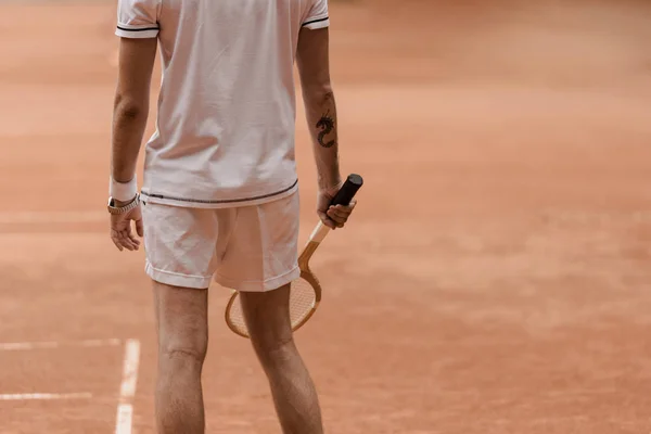 Imagen recortada de jugador de tenis de pie con raqueta en la cancha de tenis - foto de stock
