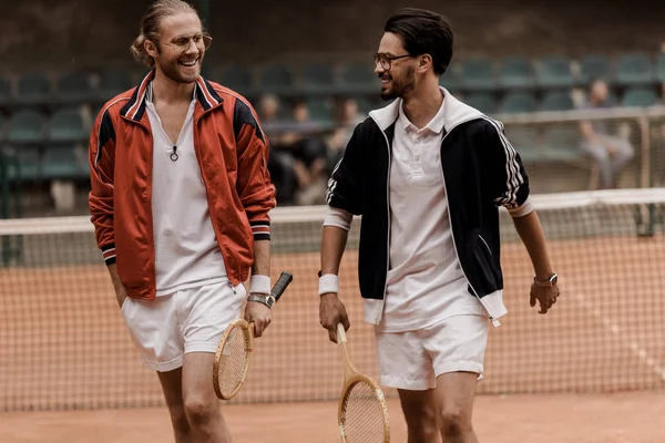 Smiling retro styled tennis players walking and looking at each other at tennis court — Stock Photo