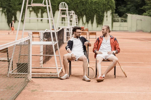 Tennisspieler im Retro-Stil ruhen sich auf Stühlen am Tennisplatz aus — Stockfoto