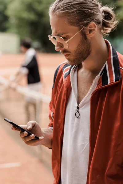 Retro styled tennis player looking at smartphone at court — Stock Photo