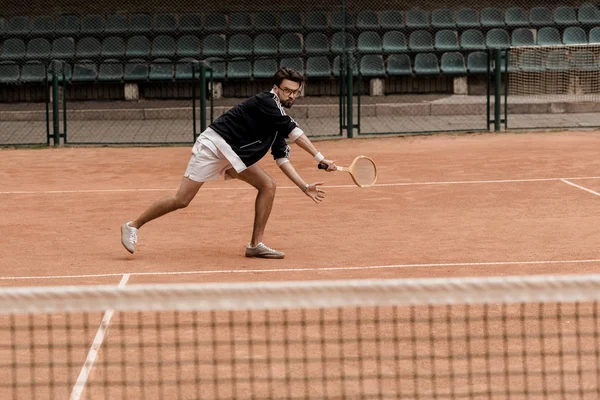 Retro estilo guapo hombre jugando tenis con raqueta en pista de tenis - foto de stock