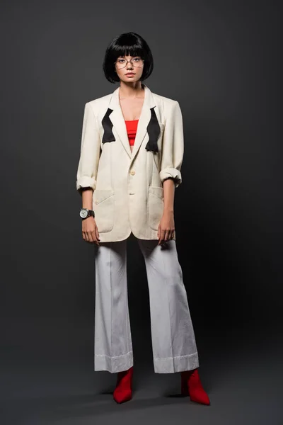 Modische junge Frau in stylischem Sakko und Klingelhöschen auf grau — Stockfoto