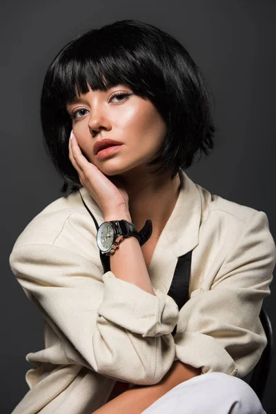 Close-up portrait of young woman in stylish jacket with male wrist watch isolated on grey — Stock Photo