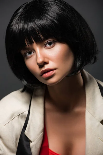 Retrato de cerca de la hermosa mujer joven en chaqueta elegante y corbata desatada mirando a la cámara aislada en gris - foto de stock