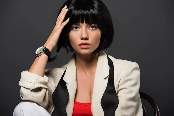 Bela jovem mulher com cabelo bobbed em roupas elegantes isolado em cinza — Fotografia de Stock